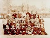 Rudbecksskolan, 30 skolbarn med lärare på skolgården.
Skolbyggnaden i bakgrunden.
Folkskollärare Agnes Björkman