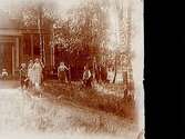 Finska motiv: Bostadshus, grupp 6 personer framför huset.Två bilder (8x8 cm) på samma glasplåt (8x17 cm).