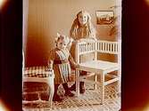 Familjebild, två flickor, Margit och Märta Lindskog. Rumsinteriör.Sam Lindskog