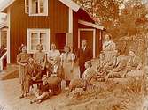 Sommarstugan, grupp 13 personer framför stugan.Sam Lindskogs familjebild.