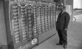 Rönneshytta Handel 4 september 1967

En man i grå kostym, vit skjorta, svart slips och grå skor står i Rönneshyttan vid en varuautomat. På automaten står: 