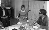 Inackorderingshem 27 april 1968

Två män och en kvinna sitter vid ett bord och pratar och dricker kaffe. På bordet ser man också vitsippor. Bakom 
dem står en tv med blommor på.