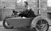 Motorcyklar 30 april 1968.
Södra Strandgatan. 
En man kör motorcykel med sidovagn, en kvinna sitter i sidovagnen.