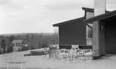 Ånnaboda 27 april 1968

Utanför ingången till Ånnaboda servering står det trädgårdsmöbler, och en skottkärra. I bakgrunden syns ett hus och Ånnaboda camping.