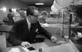 Flykting 67 17 november 1967

På postbanken sitter landshövding Valter Åman i en kassa. Vid kassan hänger det ballonger.