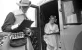 Flykting 67 17 november 1967

En kvinna och en man har teaterkläder på sig. Kvinnan sitter i en vagn och mannen står bredvid och skriver på något. Han har en myntväska på sig.