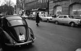Gående, första felgången 7 februari 1967

På Drottninggatan ser man Skandinaviska Banken och en del av Nikolai Kyrkan. Det står också bilar parkerade och en kvinna går över gatan.