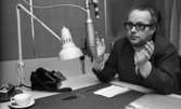 Carl-Uno Sjöblom 24 december 1968

Programmledaren Carl-Uno Sjöblom sitter vid ett bord i en studio och slår ut med händerna. Framför honom ser man en mikrofon, lampa och en telefon. Några pennor och en kaffekopp ser man också.