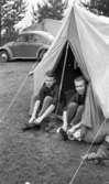 Campingplatsen bra i Gustavsvik 12 juli 1965

Två yngre män sitter i tältöppning och sätter på sig skor