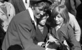 Knytkalaset 5 juli 1965.

En jubileumsvärdinna med fyra barn. En flicka håller en korg med en kattunge i. Åskådare runtomkring.