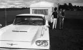 Camping 5 juli 1965.

Familj bestående av mor, far och liten flicka stående vid bil med husvagn.
