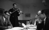 Knätofsmöte i Idrottshuset, 16 juli 1965.

Musiker i folkdräkt spelar fiol för tre herrar som har sammanträde i Idrottshuset.