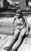 Modet 20 maj 1966

En mannekäng i en kort ärmlös klänning sitter på ett trappsteg utomhus i en park. Hon ler. I bakgrunden syns ett antal människor sitta på en parkbänk samt en annan som sitter på ett annat ställe.