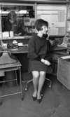 Plånböcker 27 april 1966

En kvinna talar i telefon på ett litet kontor