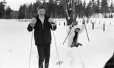 Hästnäs, 20 januari 1966

På bilden syns det en pojke och en flicka som är klädda i vinterkläder. Pojken står på skidor och flickan ser ut att ramla. Marken på bilden är täckt med snö.