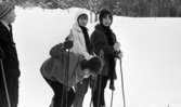 Hästnäs, 20 januari 1966

I mitten av bildens förgrund syns det tre flickor som står på skidor i djup snö. Till vänster i står en pojke som är klädd i  en stickad skärmmössa, jacka och byxor. Alla har skidstavar i händerna.