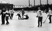 Hot rod, Kungälv - Örebro, 7 januari 1966

På bilden syns bandyspelare i isrinken. En spelare har ramlat och får hjälp av en annan spelare att ta sig upp igen. Reklamskyltar som 'Pripps', 'Zingo' m.m.  syns i bakgrunden. Publik står på läktaren i bakgrunden.