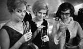 Premiär Fröken Julie, 28 februari 1966

På bilden i förgrunden syns det tre kvinnor under pausen av en teaterföreställning. Den ena kvinnan är klädd i en virkad kofta samt klänning. Under sin vänstra arm har hon klämt fast en kuvertväska. De andra två har klänningar samt pärlhalsband. De håller i tre drinkglas med sugrör. I bakgrunden skymtar man en kostymklädd herre.
