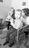 Orubricerad  5 februari 1966

Tre barn och en kvinna leker i ett rum. I centrum en pojke som reser sig ur en korgstol. Han håller en cykelbroschyr i handen. Golvet är belamrat med saker som leksaker och papper.
