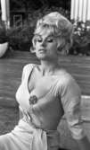 Lösa boliner, Lena...30 juli, 29 juli 1965

En skådespelerska uppflugen på en stor låda. Hon har en stor brosch på barmen som är fastsatt på klänningen. Hon blundar behagfullt.