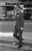 Andersson Gustavsson mode 23 april 1966

En manlig fotomodell visar herrkläder. Han är iklädd kostym, skjorta, slips och skor. I bakgrunden syns ett hus med texten 