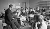 Engelsk lärare 6 april 1966

En lärare i engelska sitter på en skolbänk och blickar ut över och undervisar eleverna i sin klass.










































































































or. Han går nedför en kort trappa utomhus.