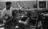 Nytt lyftsystem i bil, 18 februari 1966

I förgrunden syns det en bil med bakrutorna synliga. Bakom bilen till vänster står det en man som är klädd i en ljus arbetsrock och en mörk keps. Andra bilar skymtar i bakgrunden.