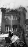 Noraskola brinner, 18 februari 1966

Det brinner i en skola i Nora. Tre brandmän syns på bilden. De är klädda i branduniformer med hjälmar till. Två av dem har riktat en brandspruta mot ett par fönster upptill mot husfasaden. På taket är det stor rökutveckling.