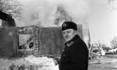 Nora-branden efteråt, 19 februari 1966

Ett brandbefäl står framför en utbränd skola i Nora. Istappar hänger från resterna av byggnaden i bildens bakgrund. Det är rökutveckling.