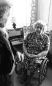 Handikappad får drömbostad 22 januari 1966

Äldre kvinna i rullstol i ett sovrum, hon tittar upp på en äldre man som står i förgrunden och tittar ned på kvinnan i rullstol
