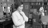 Hemma hos Ignell 8 januari 1966

Porträtt av medelålders kvinna i vardagsrum framför bokhylla, i bakgrunden syns antikviteter och konst, i ett tidningsställ skymtar Life Magazine
