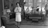 Hemma hos Ignell 8 januari 1966

Porträtt av medelålders kvinna i vardagsrum framför fönster, framför fönstret står äldre barockt skrivbord, på golvet en matta av persiskt snitt, i rummet finns ett antal föremål av antikvitetstyp, bakom kvinnan skymtar en TV