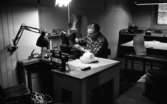 Hattfabrik läggs ned 1 mars 1966

En arbetare på ett hattmakeri sitter vid en symaskin och jobbar. På bordet framför honom ligger en vit hatt, en sax samt till vänster en massa trådrullar. Ytterligare arbetsbord och en bänk fylld av hattar syns i bakgrunden.