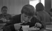 Barnbespisning 1 april 1966

En ung pojke klädd i tröja och skjorta sitter vid ett bord i en matsal och äter. Han har ett glas med mjölk framför sig. Det står på bordet. I bakgrunden syns flera barn som sitter och äter.


























































































































or. Han går nedför en kort trappa utomhus.