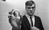 Hittegodset 31 mars 1966

En ung man klädd i vit skjorta, mörk slips, mörk tröja samt glasögon uppvisar löständer som han håller i sin högra hand.




























































































































































































































































































or. Han går nedför en kort trappa utomhus.