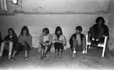 Oläslig rubrik 23 augusti 1965
 
Fem tonåringar sitter på golvet i en källarlokal. En kille sitter i en vit stol till höger.