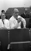Regionsjukhuset 25 november 1965

En läkare i vit rock talar inför andra läkare i en undervisningssal på Regionsjukhuset i Örebro. Läkaren till vänster om honom har en cigarett i munnen.