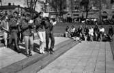 Våren 29 april 1966

En mässingsorkester går spelande genom en park i centrala Örebro. I bakgrunden sitter publik och betraktar dem.