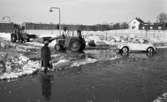 Snömodd och översvämning, 1 februari 1966
Bil, traktor och kvinna i vattensamling på vintrig gata