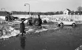 Snömodd och översvämning, 1 februari 1966
Bil, traktor och kvinna i vattensamling på vintrig gata