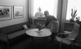 Yrkesskolan Älvtomta 25 april 1966

En elev vid en yrkesskola i Älvtomta med inriktning mot hushållskunskap böjer sig fram och sätter en blombukett i en vas på ett runt bord i ett vardagsrum. En fåtölj står vid bordet. en stor lampa hänger över bordet. Hon är klädd en i kort, mörk klänning och har ett ljusrandigt förkläde på sig. I bakgrunden står en stor soffa och över den hänger två tavlor på väggen.