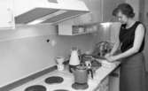 Byggspecial Oxhagen 11 februari 1966

I ett kök i en lägenhet i Oxhagen står en kvinna och öppnar en kartong som ligger på diskbänken. På ett uppläggningsfat ligger det bullar. På spisen står en kaffekanna.