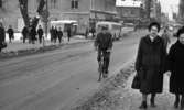 Dragos cyklar 28 januari 1966

En man cyklar klädd i rock och byxor genom centrala Örebro. På trottoaren nära honom promenerar två äldre damer varav den ena är klädd i päls. I bakgrunden syns två bussar samt bilar. Affärer, fotgängare samt en kiosk syns på andra sidan gatan. En kvinna med en barnvagn står även där. Marken är täckt av snö.