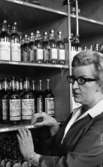 Sprithamstringen slut, 8 februari 1966

En kassörska står inne i Systembolaget vid hyllor fyllda med spritflaskor. Hon är klädd i arbetskläder.