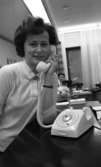 Telefonreportage, Ishockey klar 31 januari 1966

En kvinna står vid en hög disk på vilken det står en vit telefon. Hon håller dess vita lur mot örat. Hon är klädd i en vit tröja. I bakgrunden skymtar ytterligare en kvinna samt ett fönster med gardiner framför.