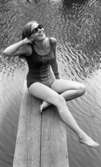 Baddräkter 30 juni 1966

En fotomodell klädd i mönstrad baddräkt och solglasögon sitter på en brygga i närheten av ett vattendrag.