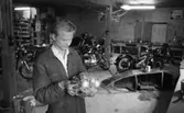 Motorcyklar, långtradare i diket 30 juni 1966

En ung man i arbetskläder håller en motor till en motorcykel i sina händer. Motorcyklar syns i bakgrunden.