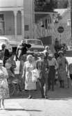 Loka brunn 2 22 juli 1966

En massa äldre damer och herrar på promenad i kurorten Loka brunn. En av damerna sitter i en rullstol. Damerna bär klänning och herrarna bär kostym. I bakgrunden syns byggnader samt bilar.