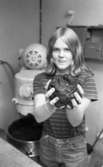 Loka brunn 22 juli 1966

En ung kvinna klädd i randig t-shirt samt jeans håller en stor klump i sina händer. I bakgrunden syns en stor maskin.