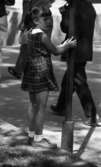 Strosor rep 2 25 juli 1966

En liten flicka klädd i rutig, kort klänning, strumpor och knytskor på fötterna samt håret i pippilottor står invid en lyktstolpe och håller i denna med händerna.